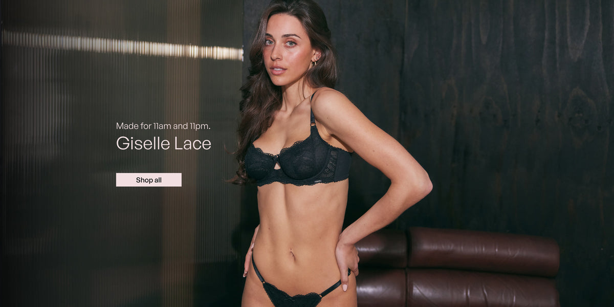 A woman modeling black lace lingerie in a dimly lit interior with dark wood paneling and a brown leather chair. White text on the left reads 'Made for 11am and 11pm.'